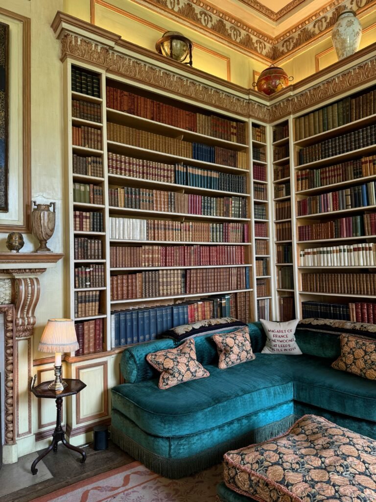 Luxurious library with vintage books and elegant decor, featuring plush teal seating.